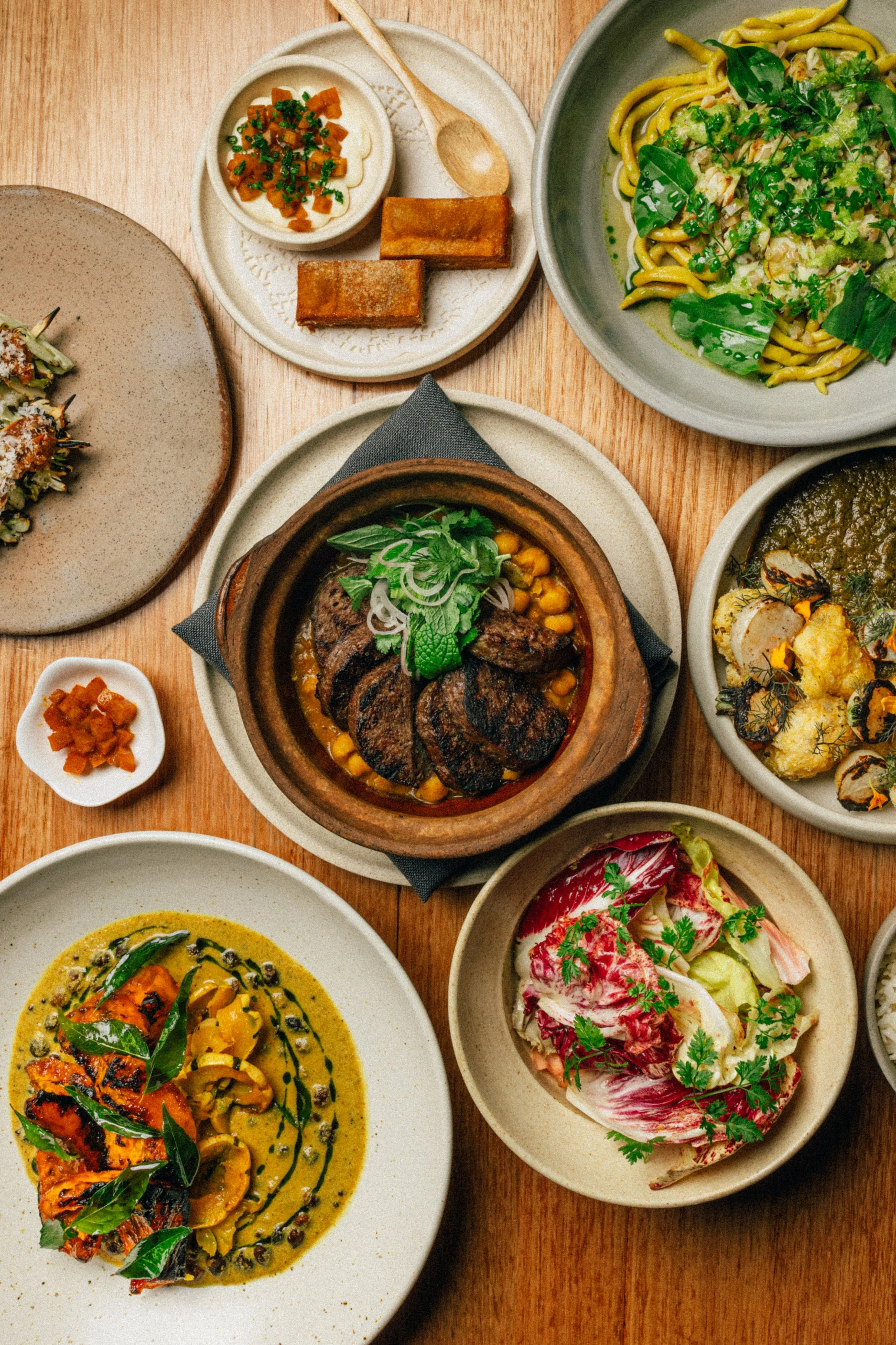 A bird's eye shot of the winter menu from a contemporary Indian restaurant in Melbourne CBDeaturing goat kebab, stewed chickpeas, roasted pumpkin and seasonal salad.