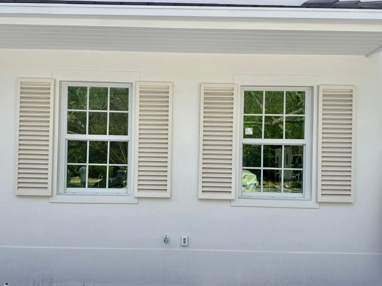 Ventanas con cristales y contraventanas blancas en una pared blanca de casa.