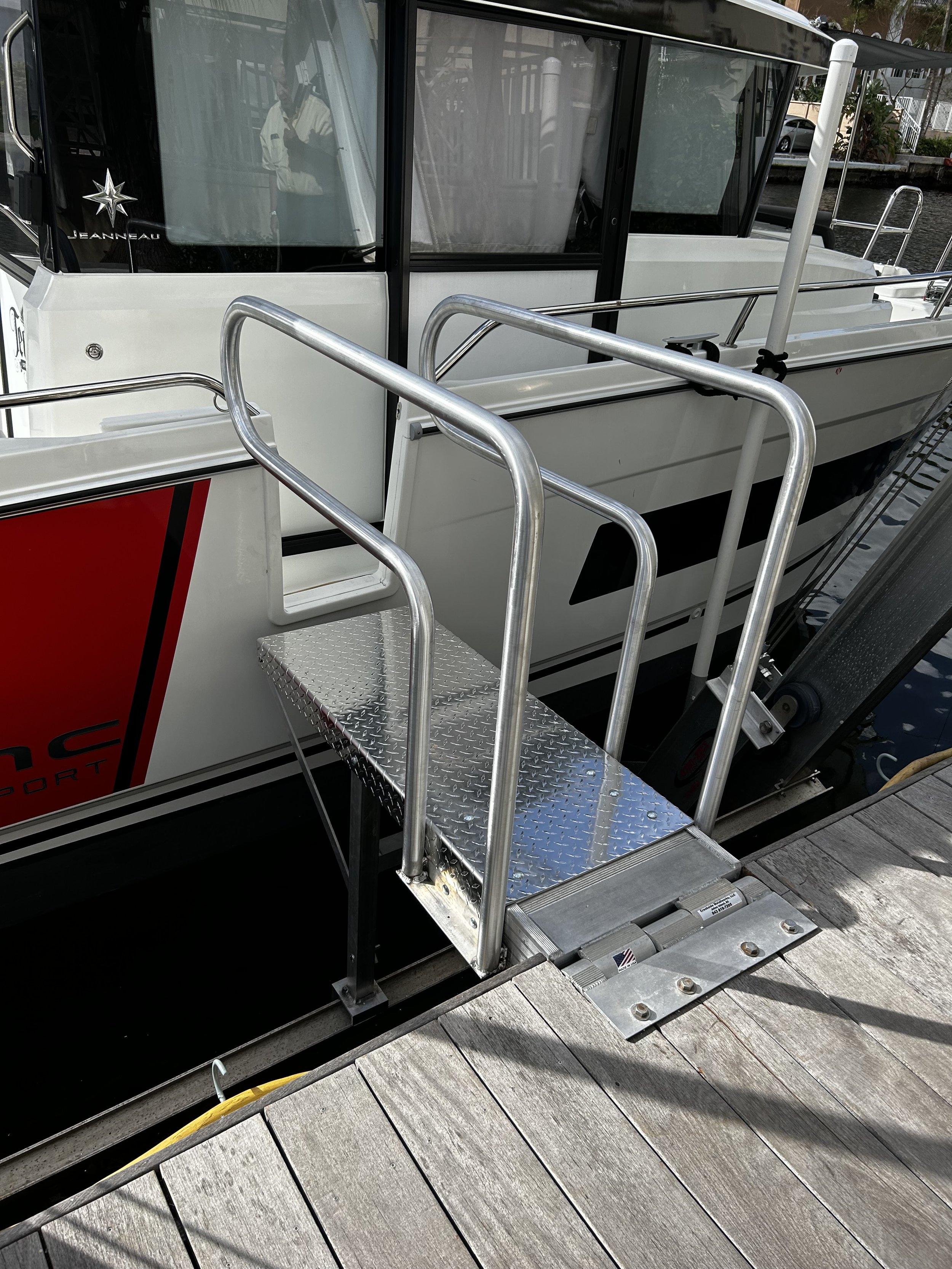 Una pasarela de metal con barandillas conduce a la puerta de un barco de pesca anclado en un muelle de madera.