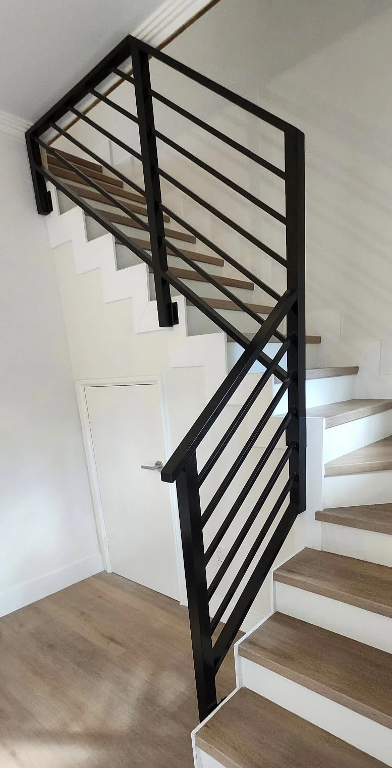 Escalera de madera con barandal de barandal de metal negro en un interior moderno.