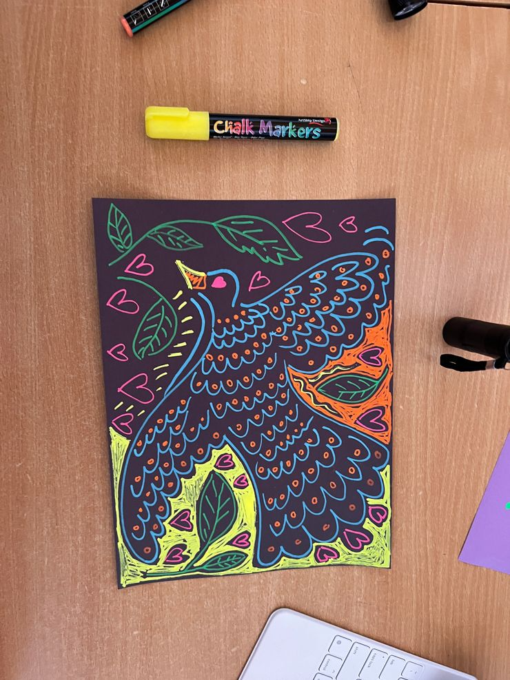 Colorful neon drawing of a peacock with hearts and leaves on black paper, created with chalk markers.