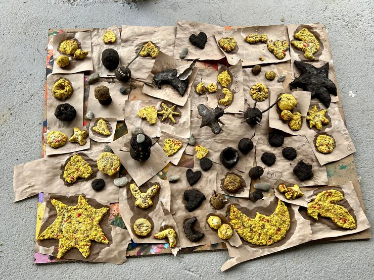 Collection of various homemade cookies and treats on brown paper on a gray surface, shaped as stars, hearts, moons, and other shapes, some decorated with colorful sprinkles.