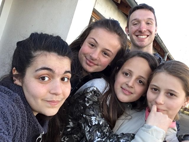 Group photo of two adults and three young girls smiling outdoors