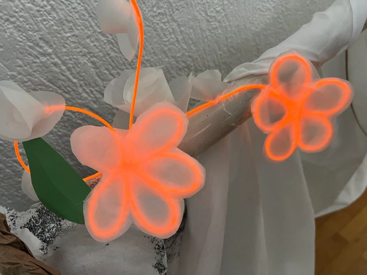 Decorative string lights shaped like orange flowers with green leaves on a wall