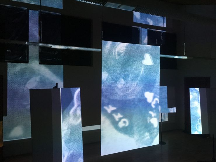 Multiple screens and columns displaying abstract, blurry images and light patterns, creating an immersive digital display environment.