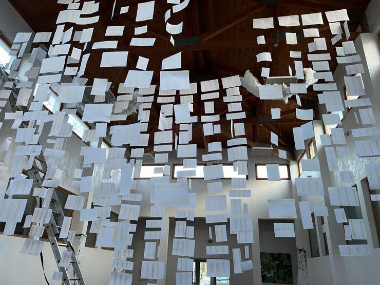 A modern interior with numerous suspended white rectangular panels hanging from a wooden ceiling.