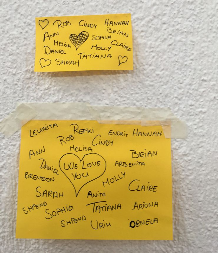 Two yellow sticky notes on a wall. The top note has names with hearts and a shaded heart. The bottom note has more names, a heart with 'WE LOVE YOU' inside, and multiple names written around.