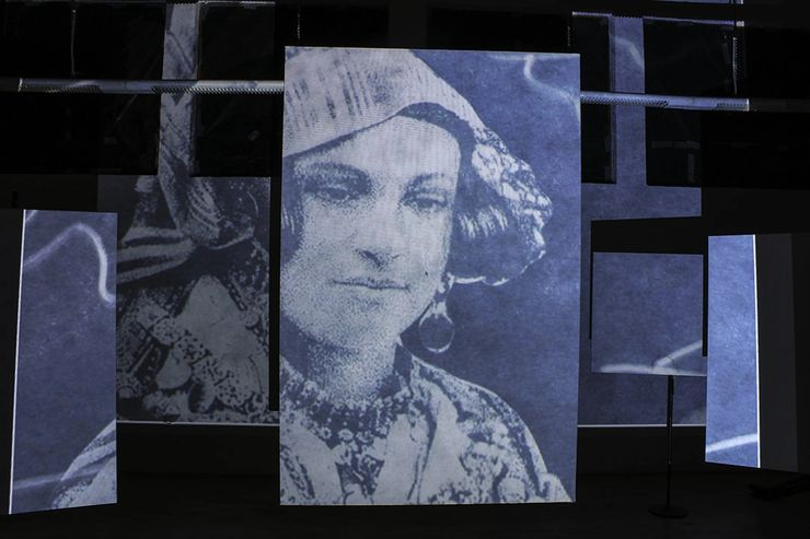 Series of large vertical screens displaying a pixelated black-and-white image of a woman with short hair and earrings, set up in an indoor space.