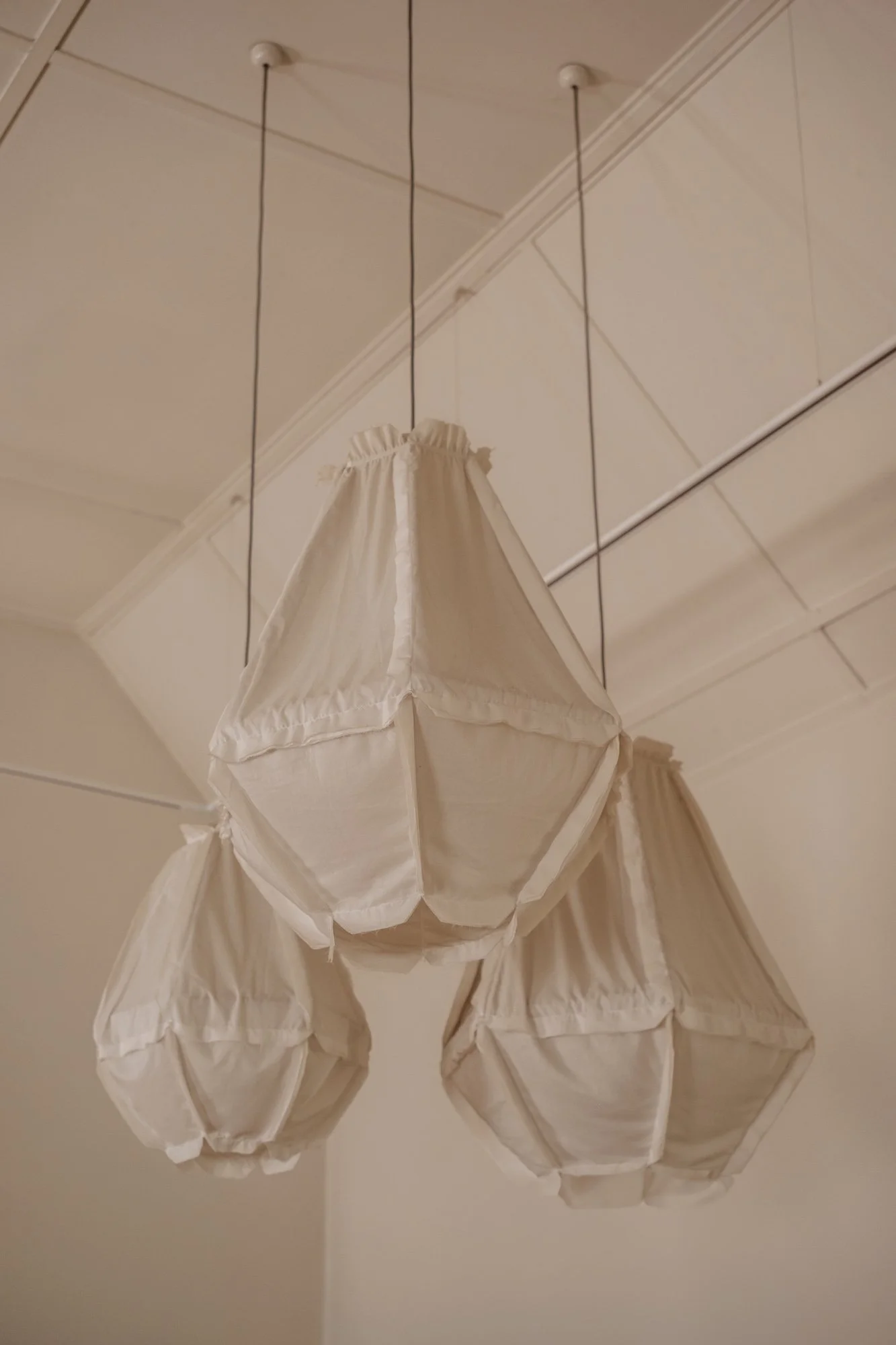 Three hanging fabric lampshades in a neutral room.