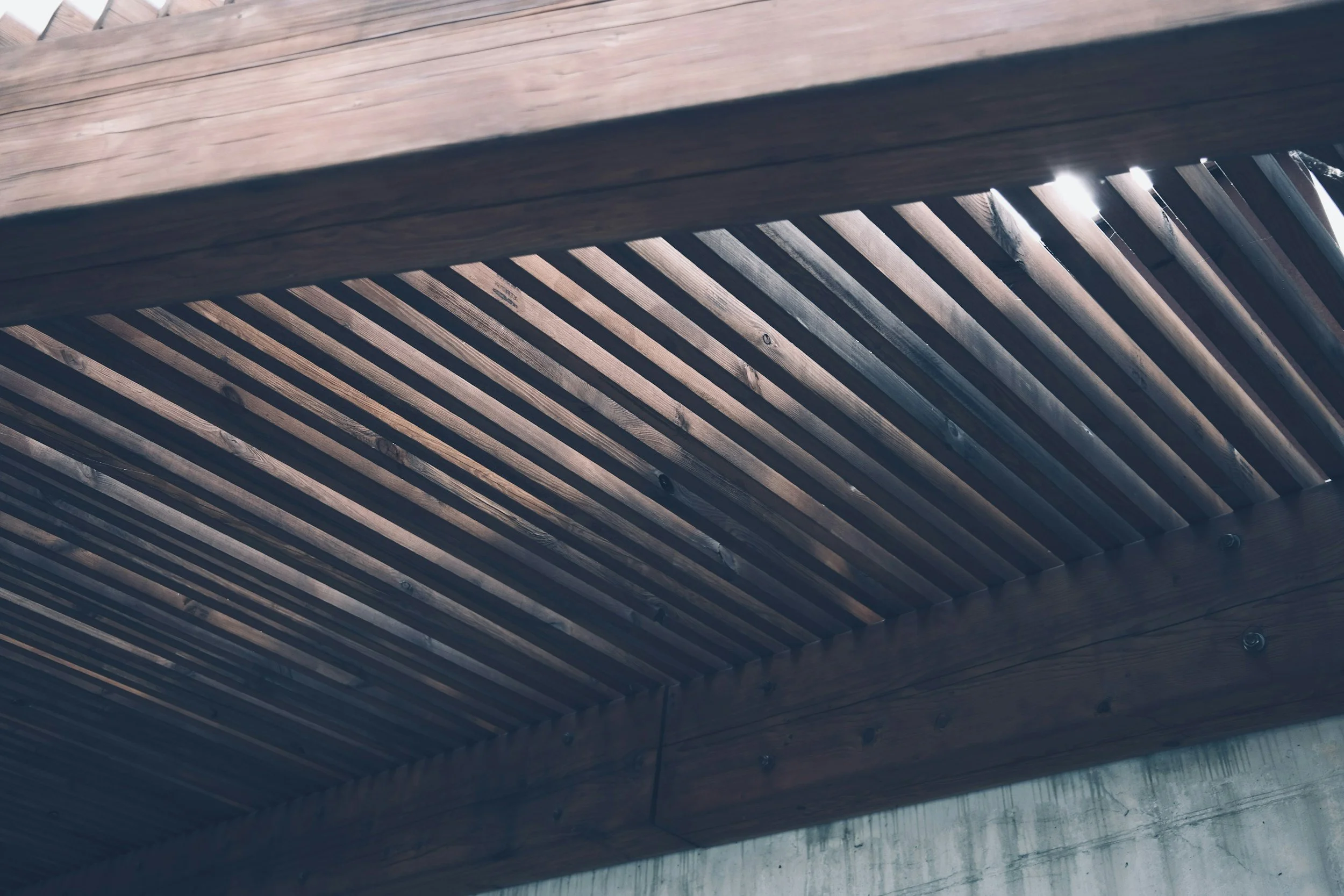 Close-up of a wooden surface with slats and beams, probably part of a ceiling or roof structure.