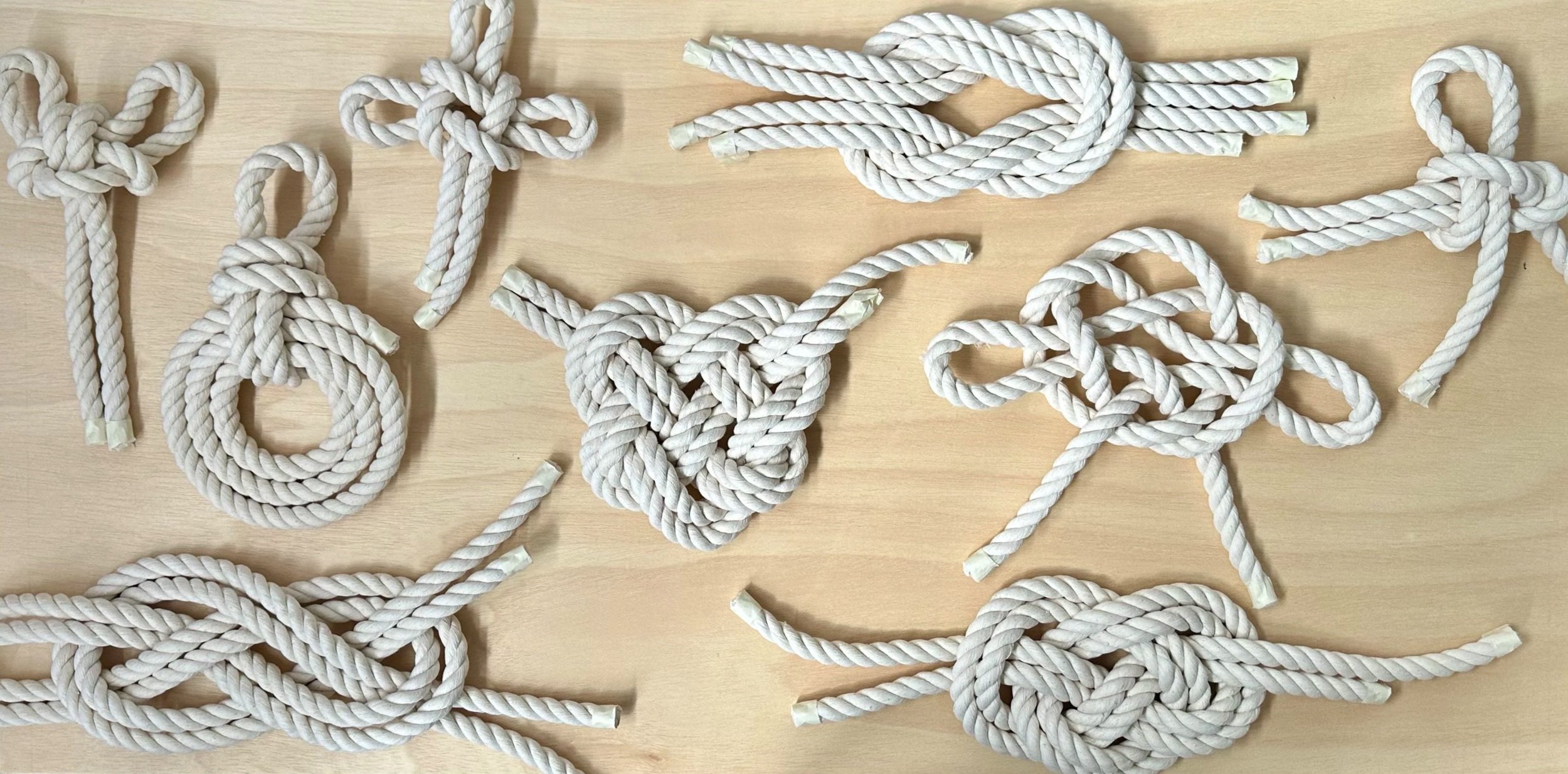 Collection of various large scale white rope sailor knots arranged on a light wooden surface | Ana Salazar Atelier