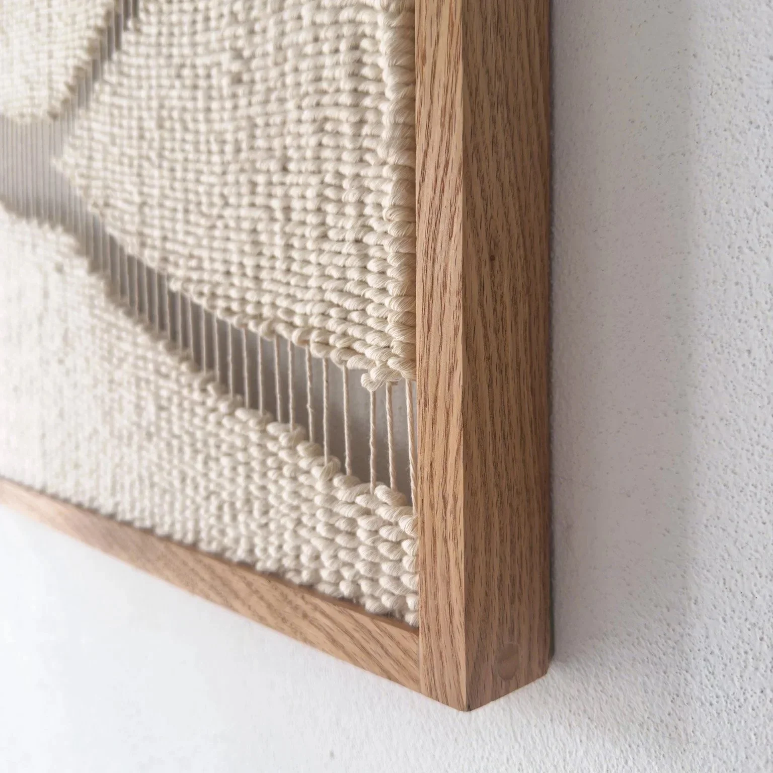 Side profile of 3D textile art showing deep shadows and the texture of natural fibers in a hand-finished wood frame