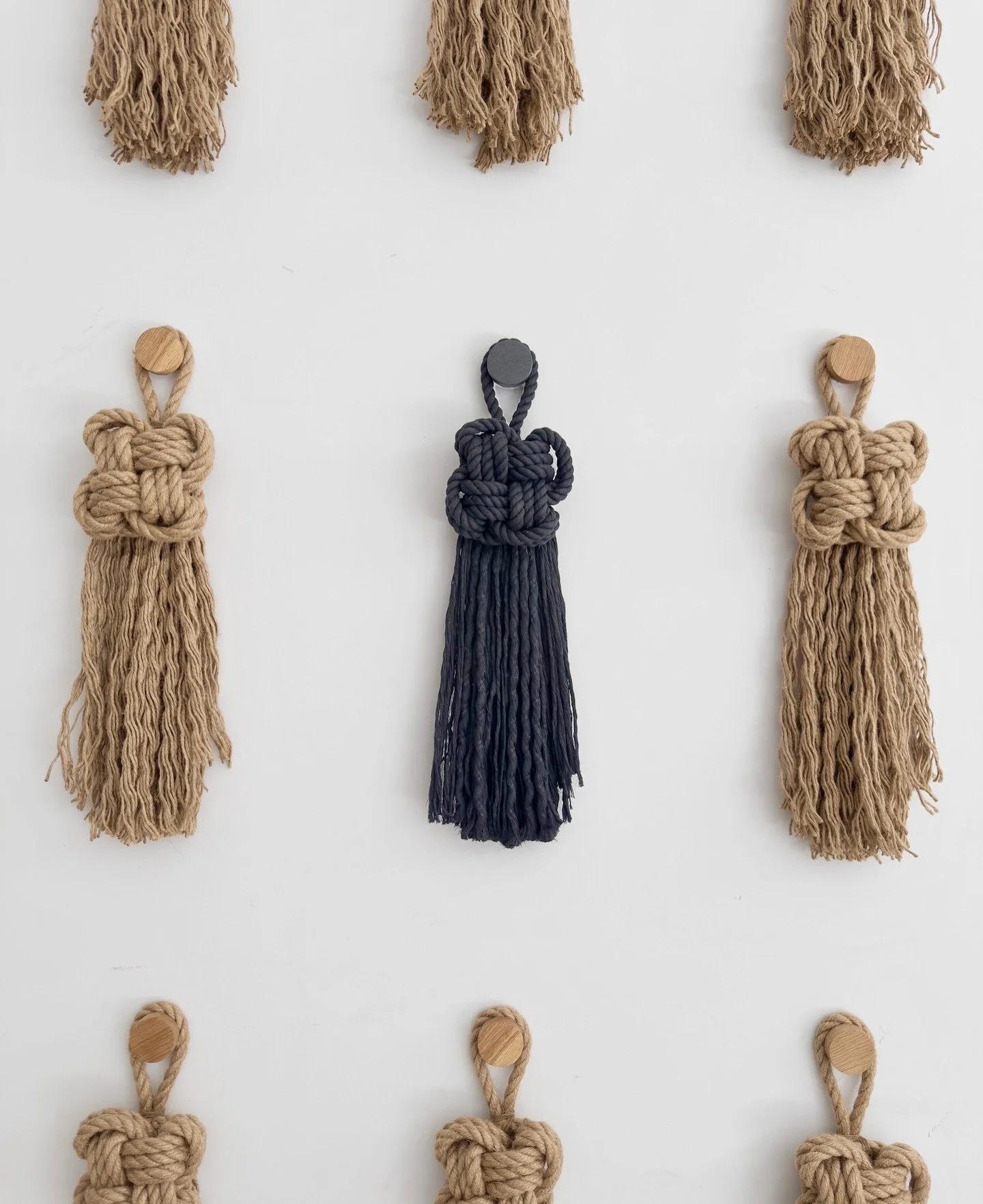 9 Knots – Wall installation by Ana Salazar featuring a grid of nine individually hand-knotted textile pieces arranged in a geometric composition.