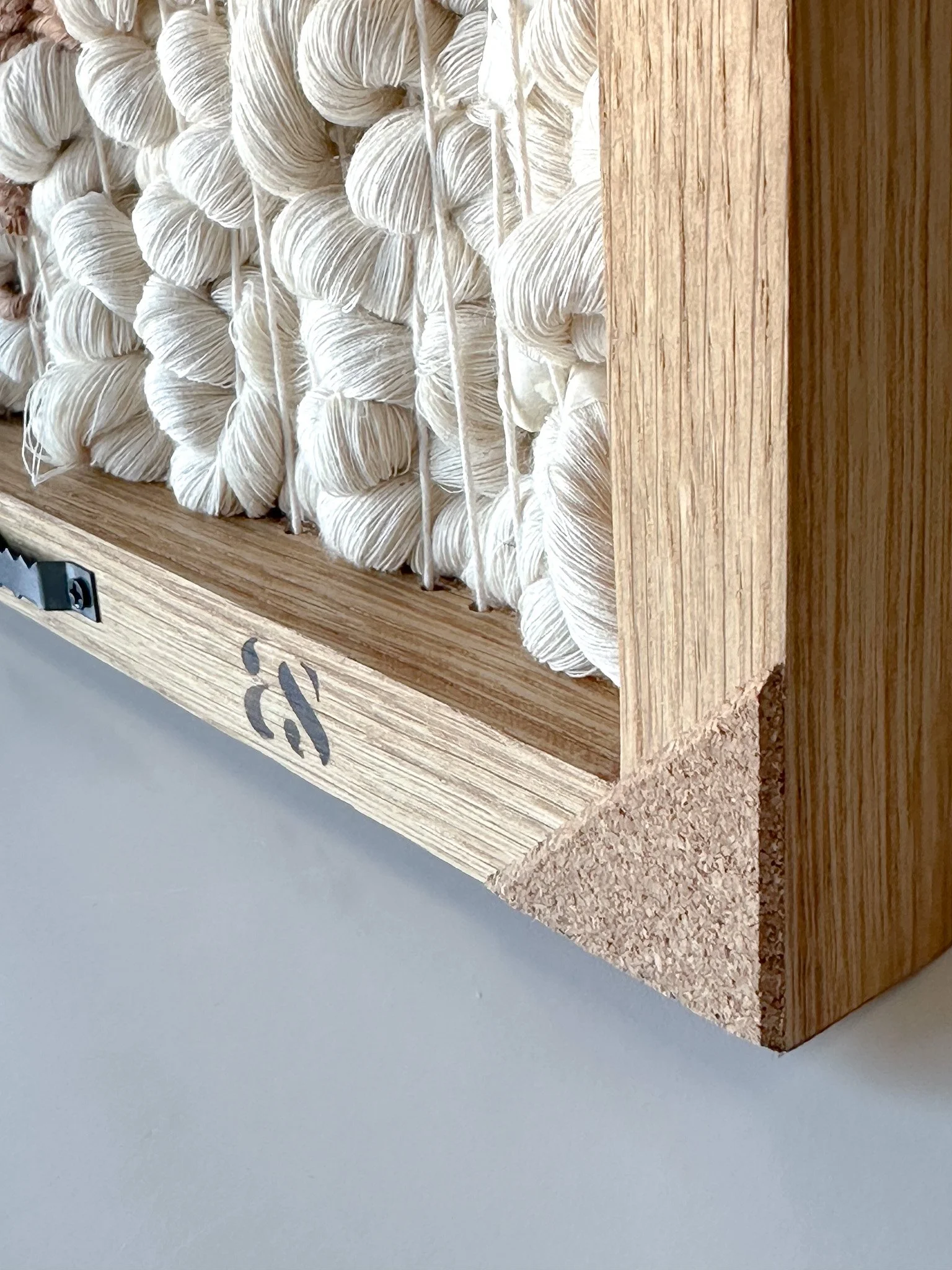 A wooden box filled with white skeins of yarn, with part of the box showing a small black logo or symbol.