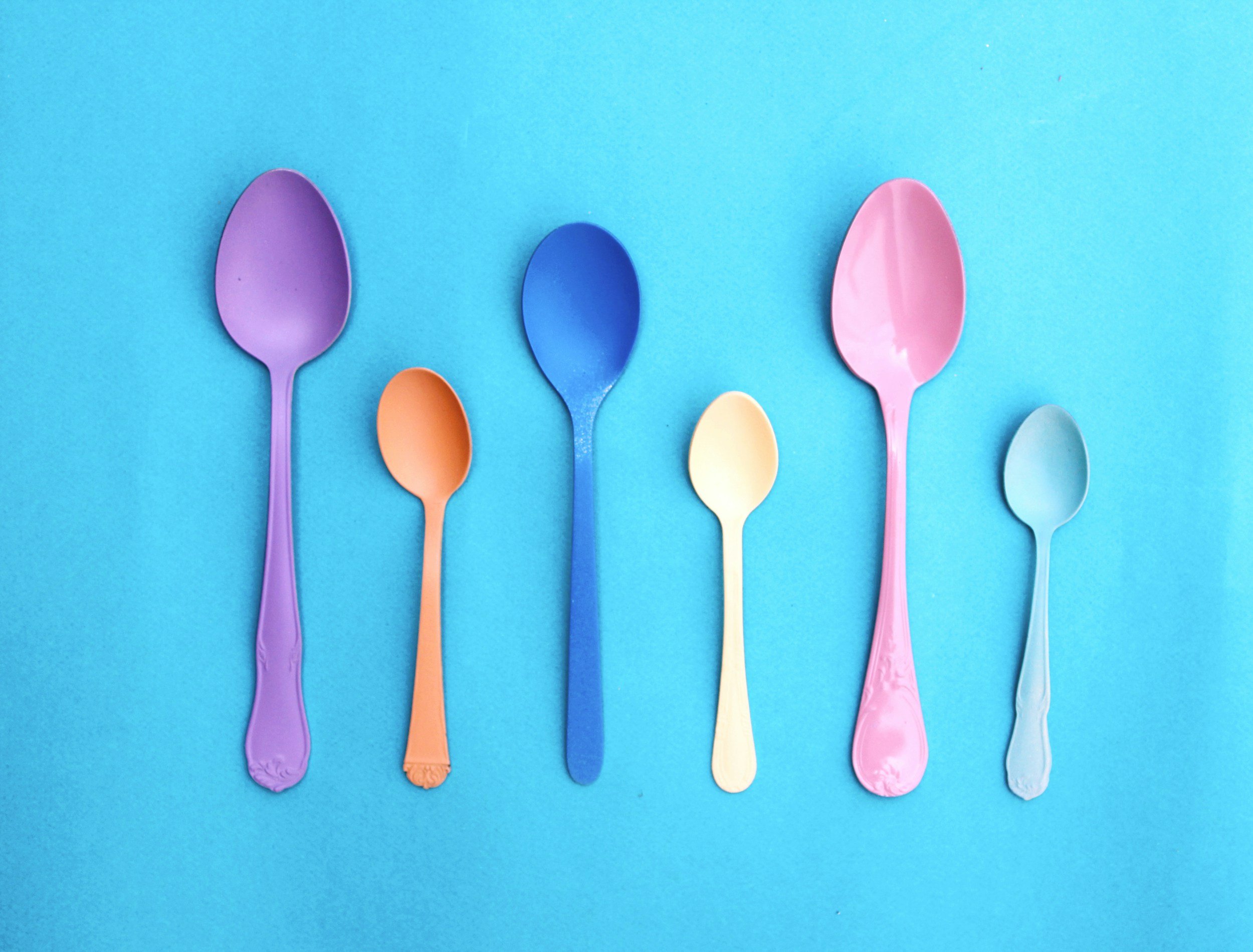 spoons of different colours and sizes lined up in a row