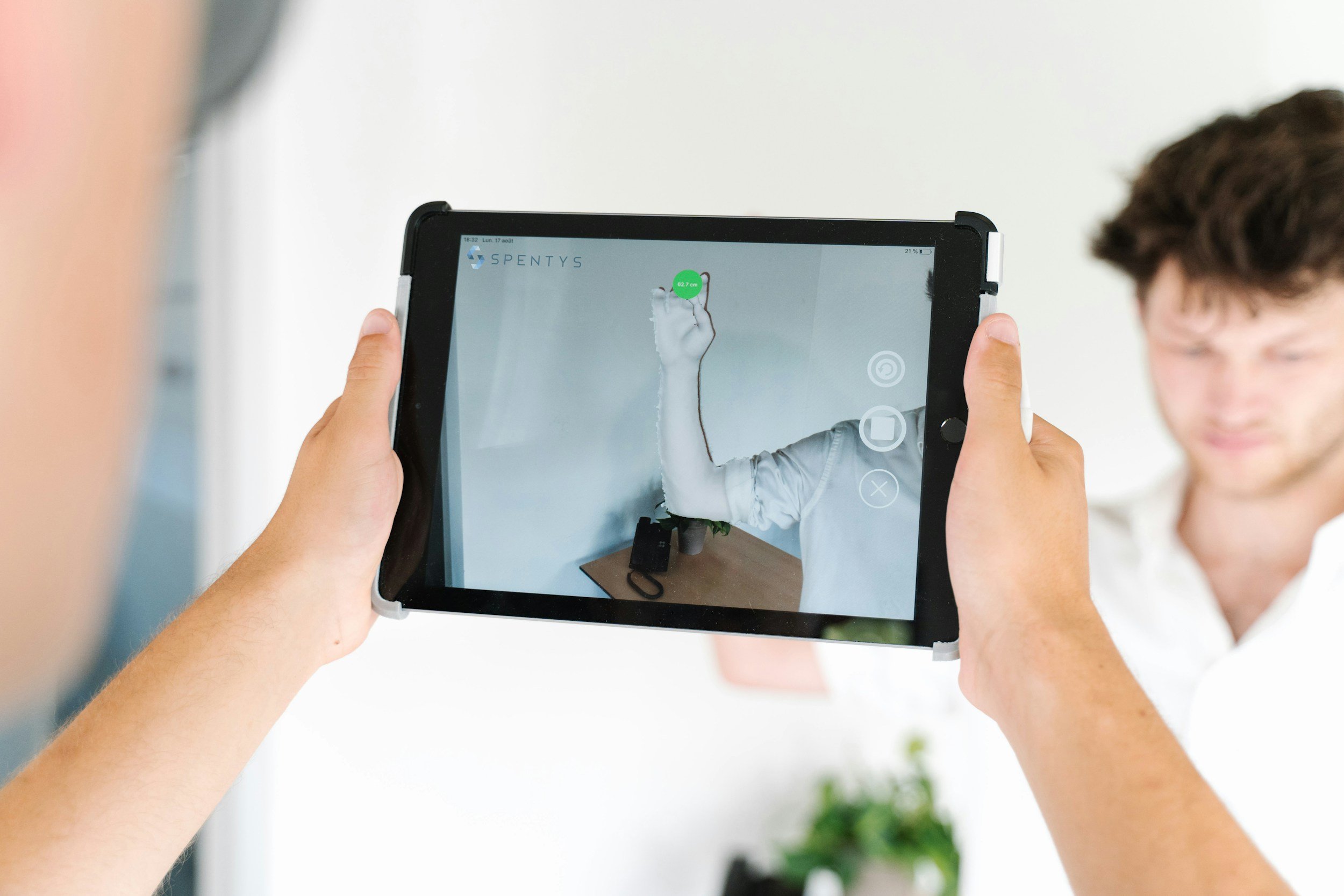 Person holding tablet displaying a 3D hand model and measurement data, with a blurred background.
