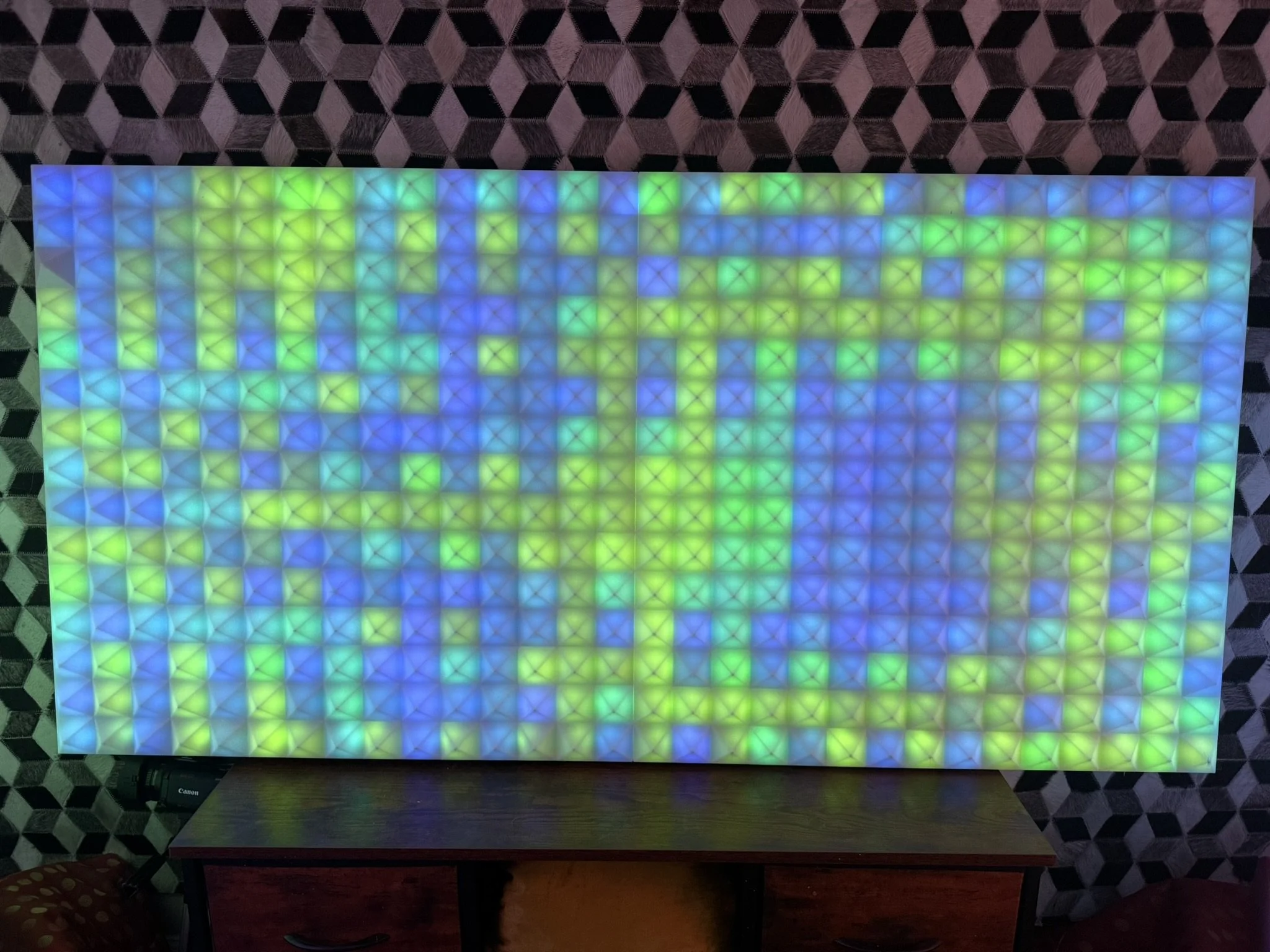 A rectangular panel with colorful glowing squares arranged in a grid, placed on a wooden table.