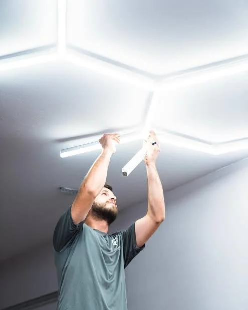 Man installing or repairing LED ceiling lights in a room.