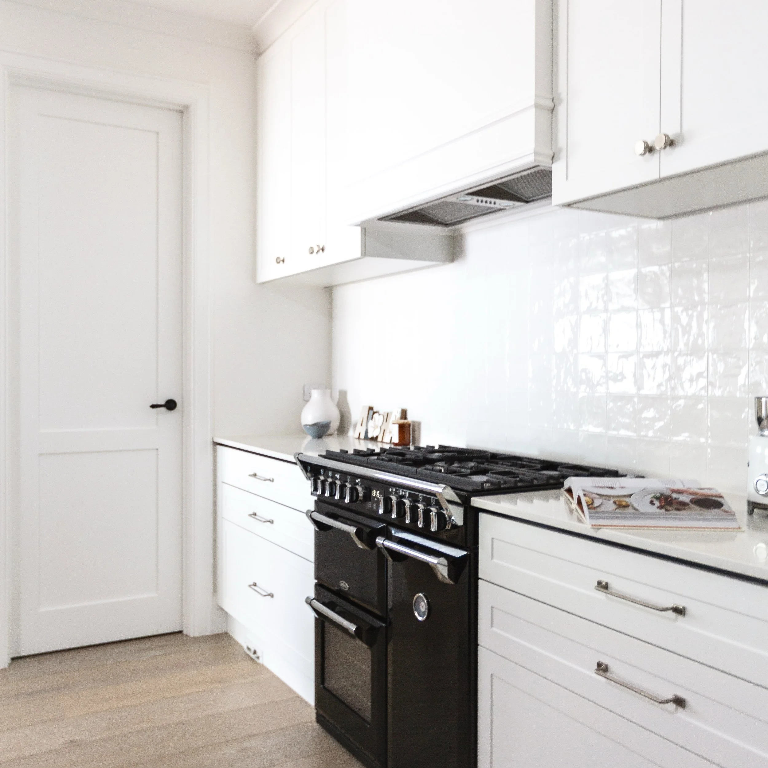 MMOUNT MARTHA / We gave this kitchen a much-needed facelift by replacing all the doors, drawers and front panels with a timeless shaker profile. We also added a beautiful feature rangehood and extended the overhead cabinetry to create a more seamless