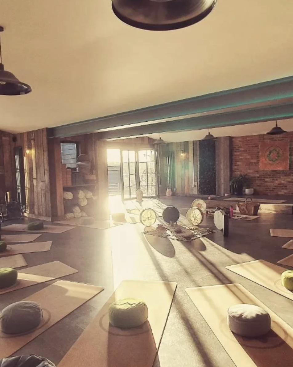 Yoga studio with mats, round cushions, and sunlight streaming through windows.