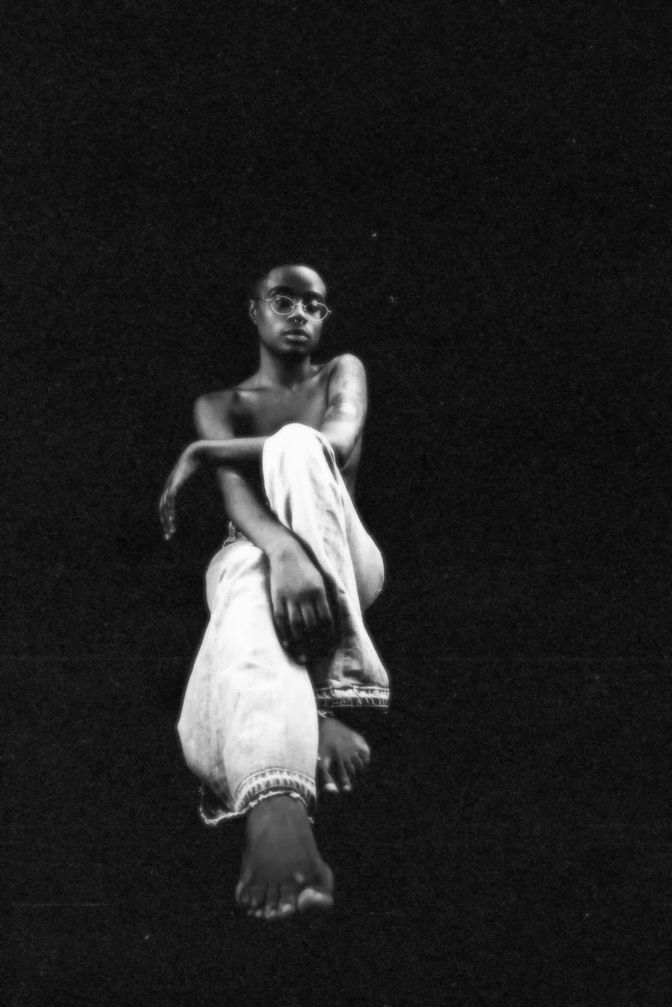 woman sitting in minimal dark setting black and white cinematic portrait photography