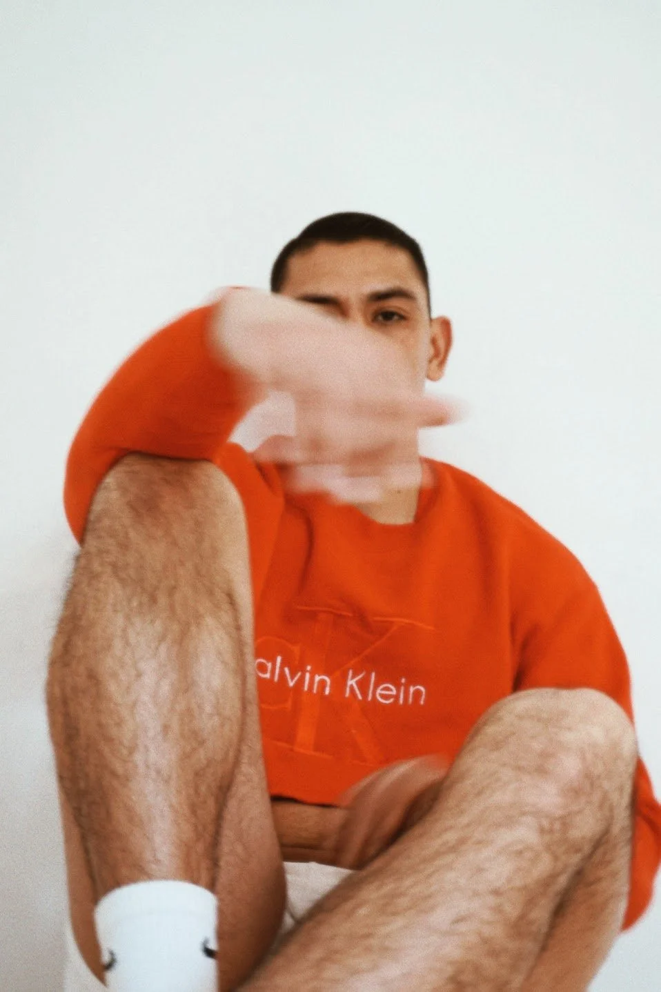 man wearing red Calvin Klein crop top sweater sitting with hand covering face editorial portrait photography Los Angeles