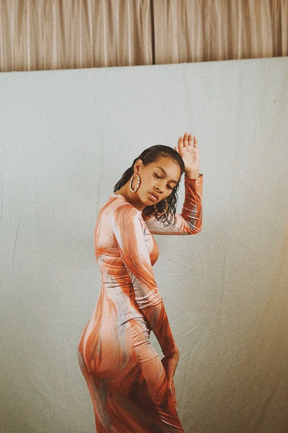 woman posing indoors wearing fitted dress with soft natural lighting