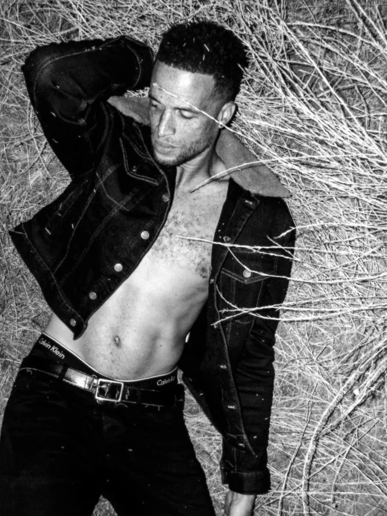 man posing in hay wearing open jacket black and white portrait photography