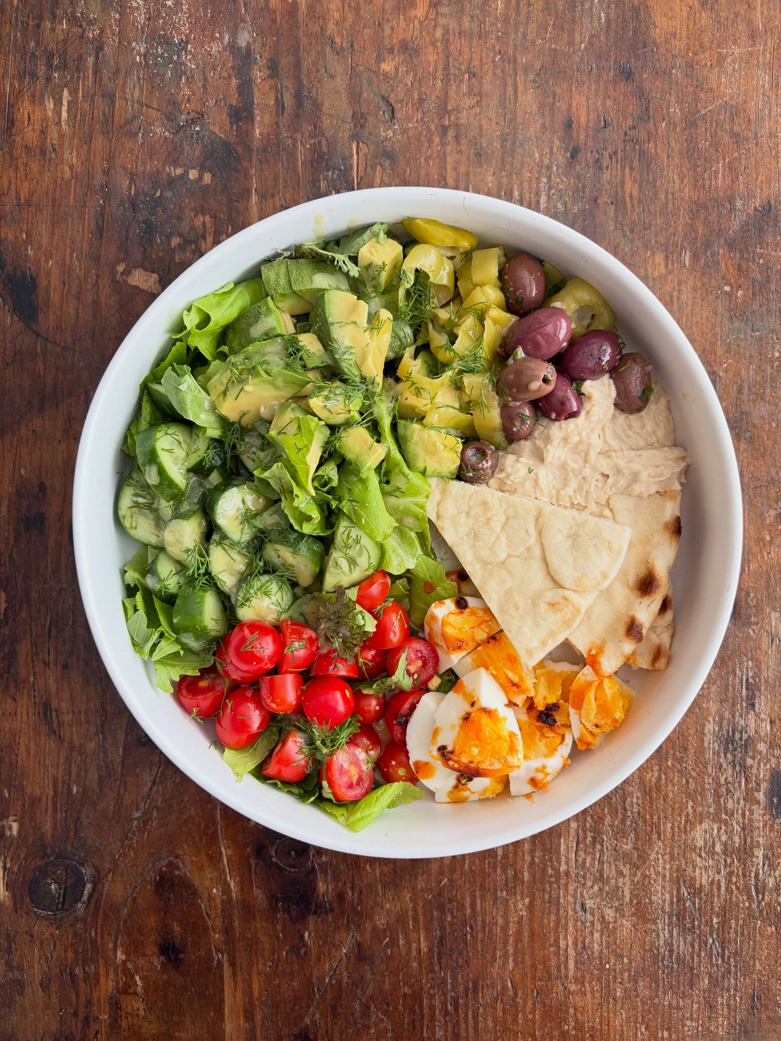 Kitchen sink salad: @jubilantfarms salad mix and cucumbers, @heartsteadfarms tomatoes, @seatongardens dill, @brothersproductsdallas hummus, olives, and pita, @nananpopllc egg, @bigpicturefoods pepperoncini, avocado from Mexico, chili oil from the Vie
