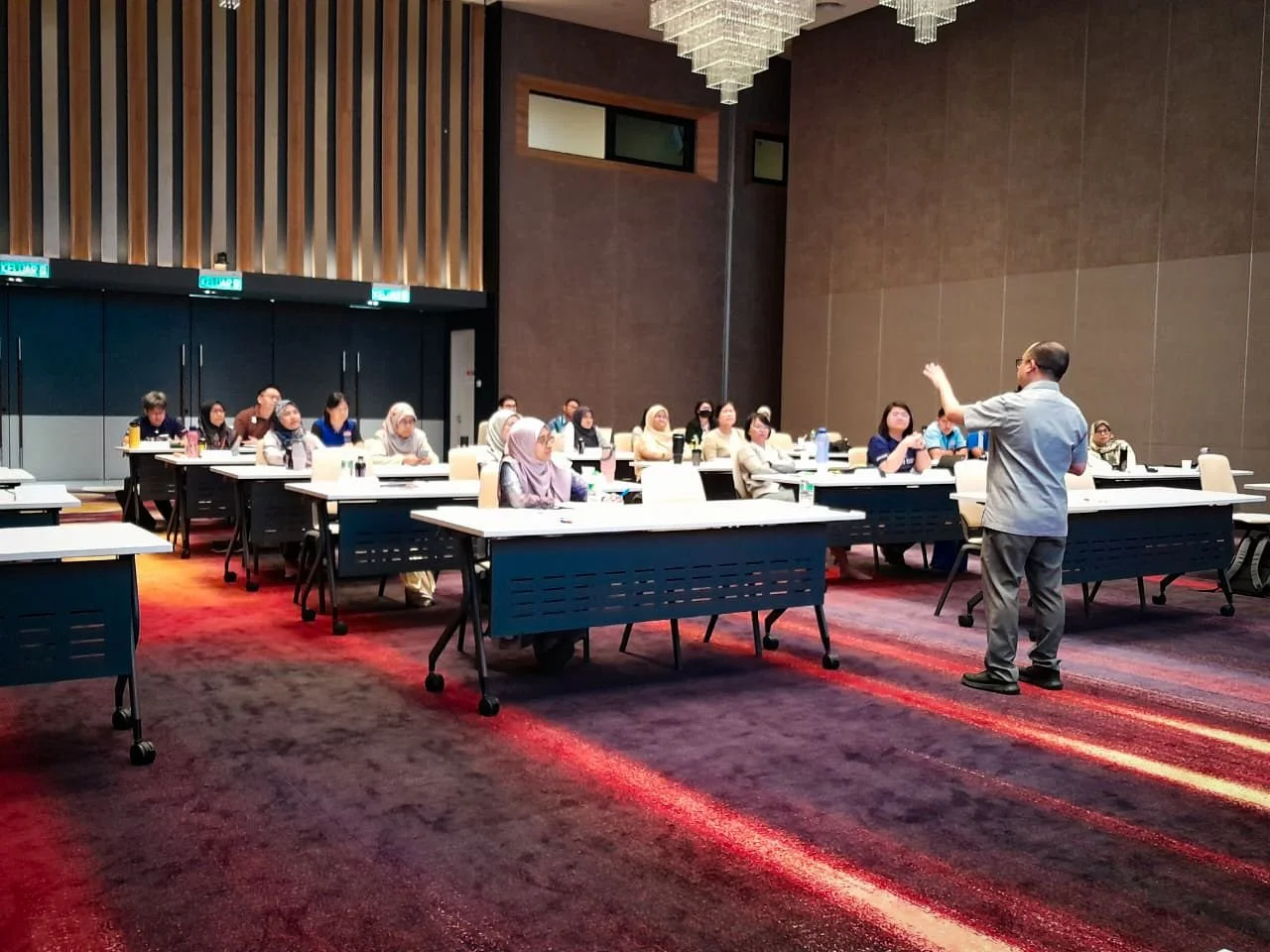 A man giving a presentation in a conference room filled with seated attendees.