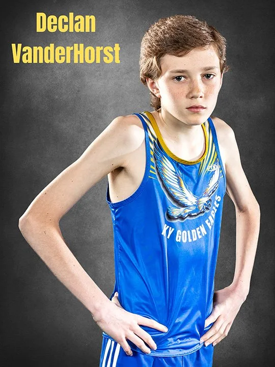 Young male athlete in a blue track uniform with a bird graphic, hands on hips, against a dark gray background, with yellow text reading "Declan VanderHorst" in the top left corner.