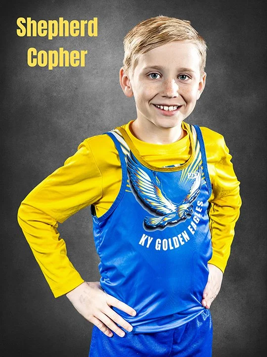 Young boy wearing a blue sports jersey with an eagle graphic and the words "NY Golden Eagles" layered over a yellow long-sleeve shirt, smiling with one hand on his hip, against a dark gray background. Captioned "Shepherd Copher" in yellow text.