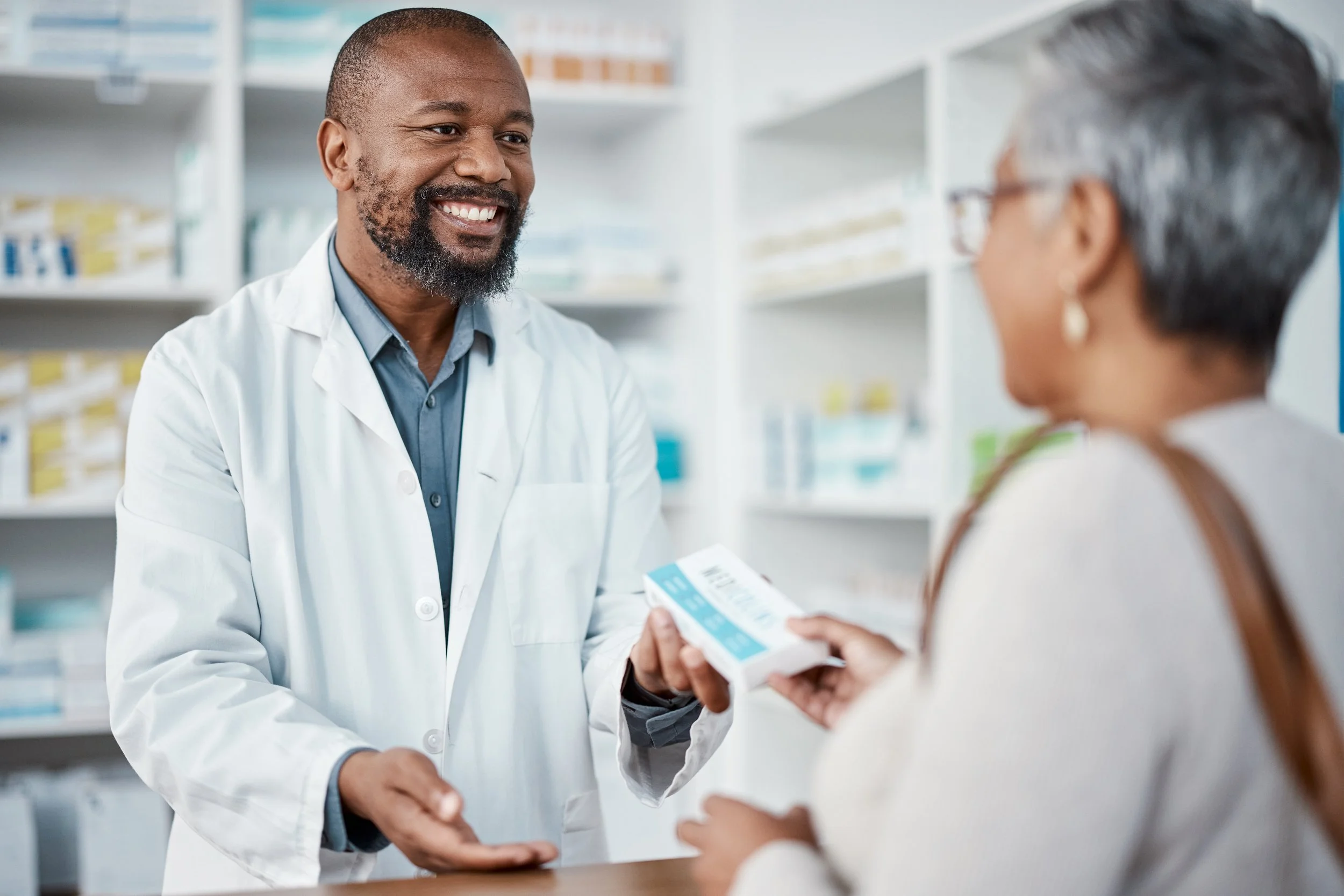 Pharmacist handing prescription medication to a senior Medicare patient.