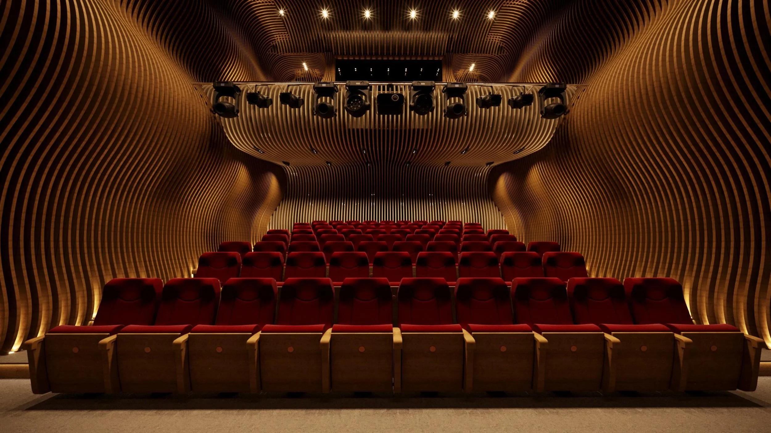 Empty theater with red seats and wooden, wavy wall and ceiling design, stage with lighting, and sound equipment.