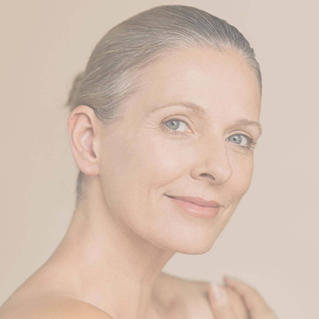 Portrait of a middle-aged woman with short, grey hair and blue eyes, smiling softly against a neutral background.