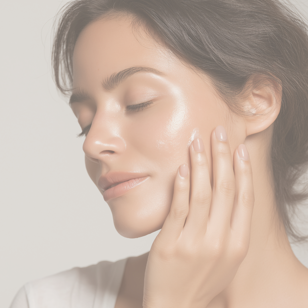 A woman with closed eyes touching her face, with glowing, clear skin.
