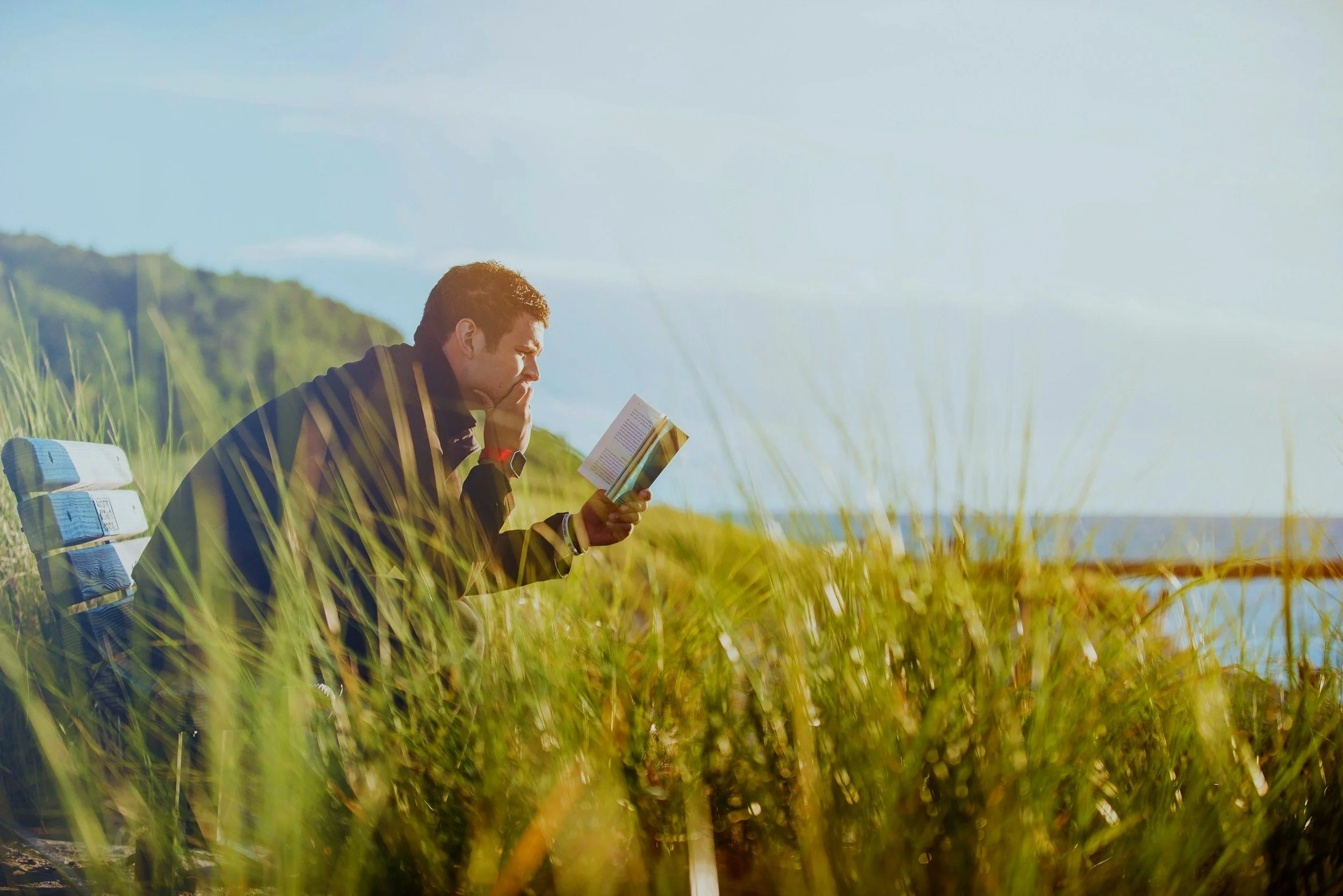 Man lying in the grass reading a book