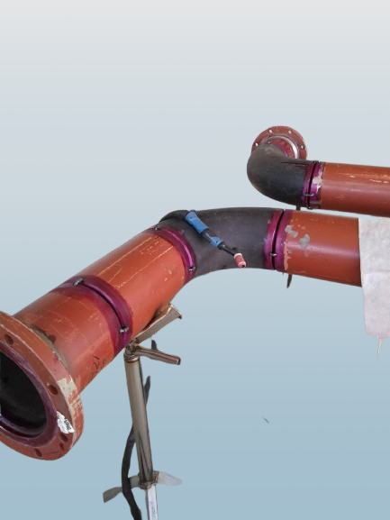 Conjunto de tubos metálicos e conexões para irrigação ou sistemas de água, apoiados por suporte metálico.