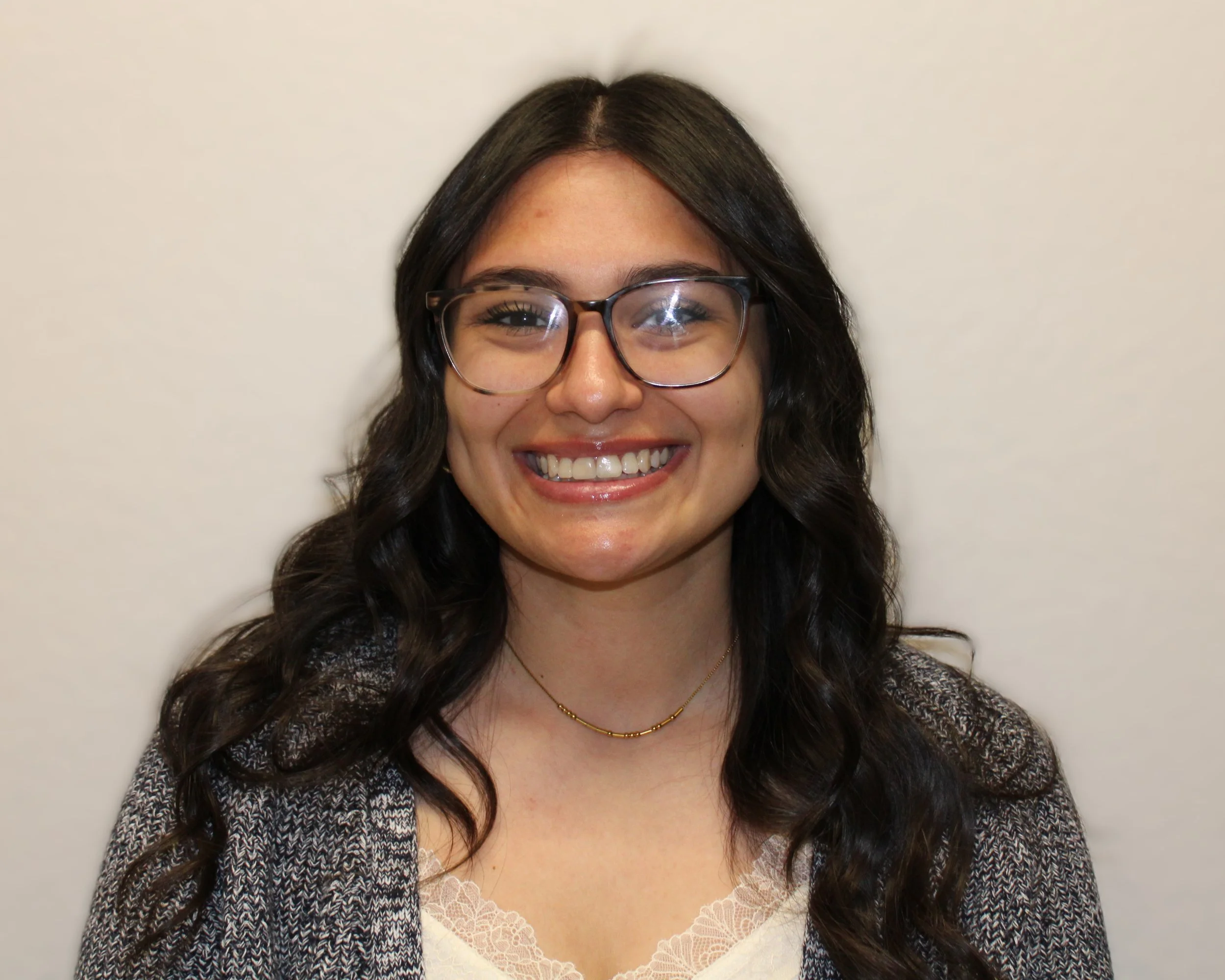 Woman with long dark hair, glasses, smiling