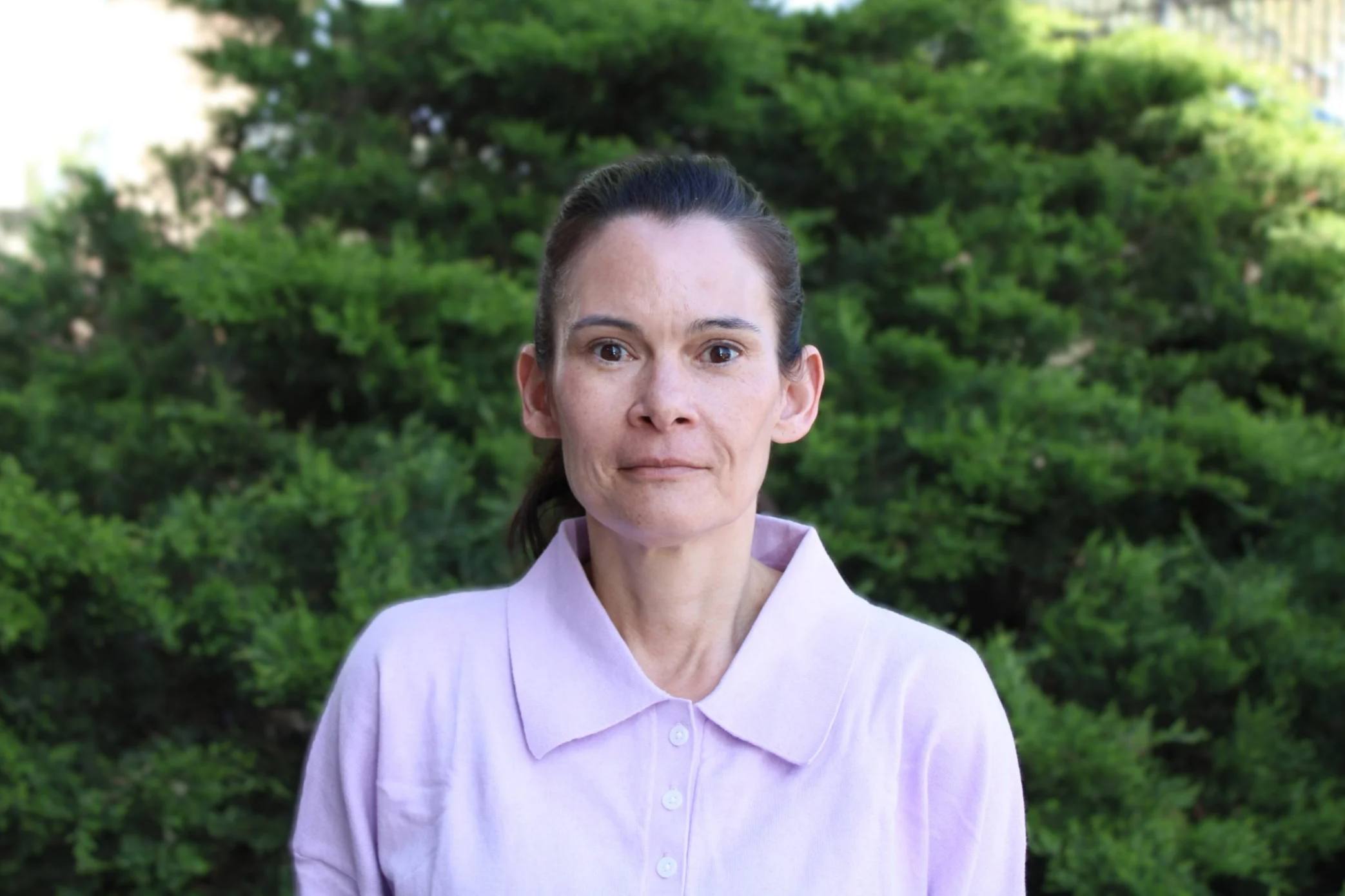 Woman with long hair pulled back, in a purple collared shirt