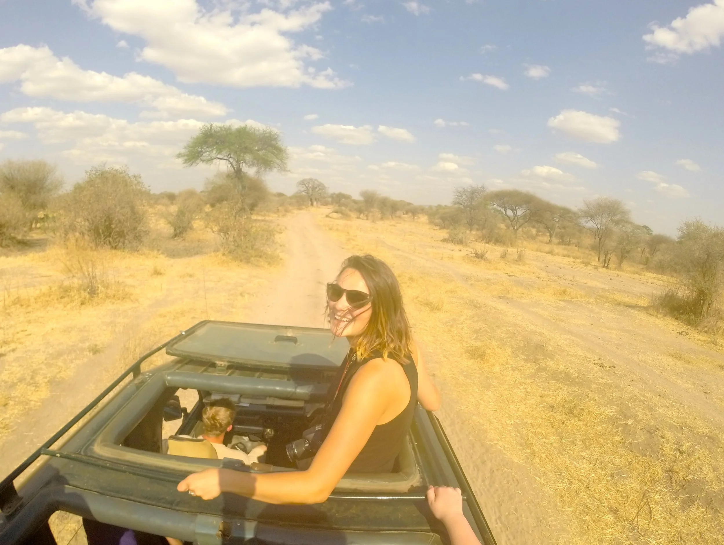 Your Vancouver WA wedding photographer smiling from a safari vehicle in a dry savanna landscape.