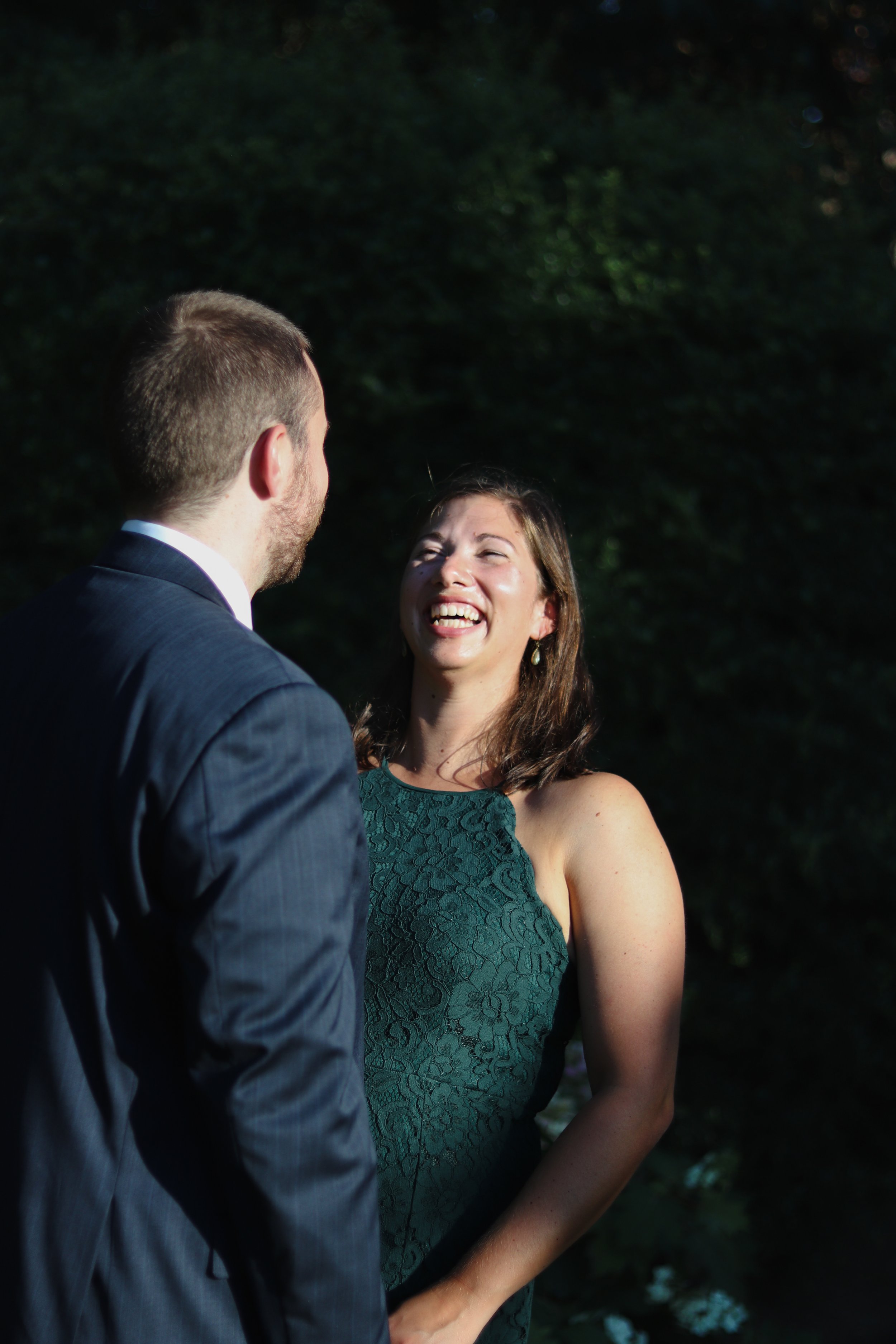 A woman in a green lace dress smiling and laughing during elopement photos in Vancouver, WA.