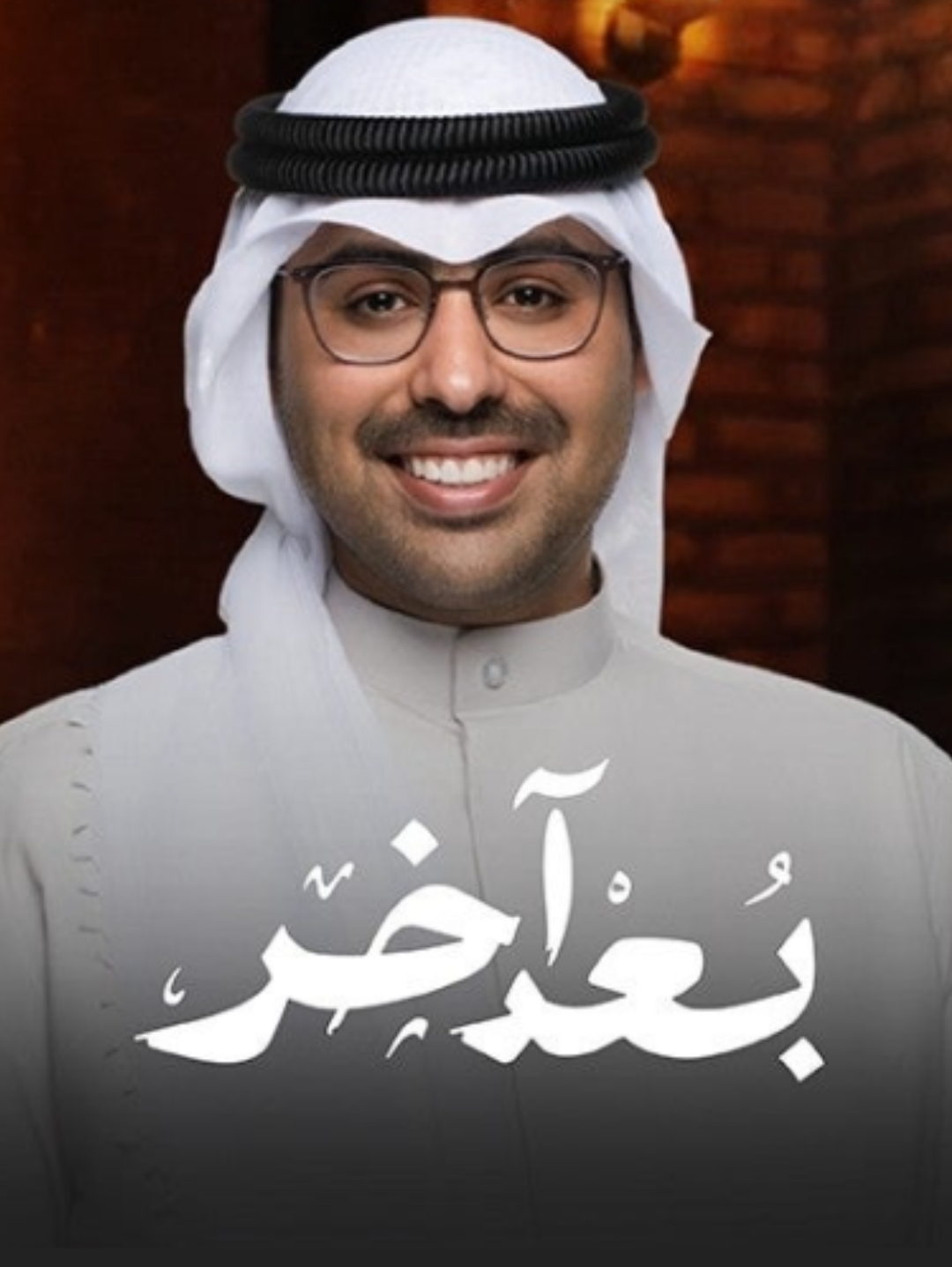 A man in traditional Middle Eastern attire, including a white head covering and glasses, smiling in front of a wooden background, with Arabic text that reads 'عيد مبارك'.