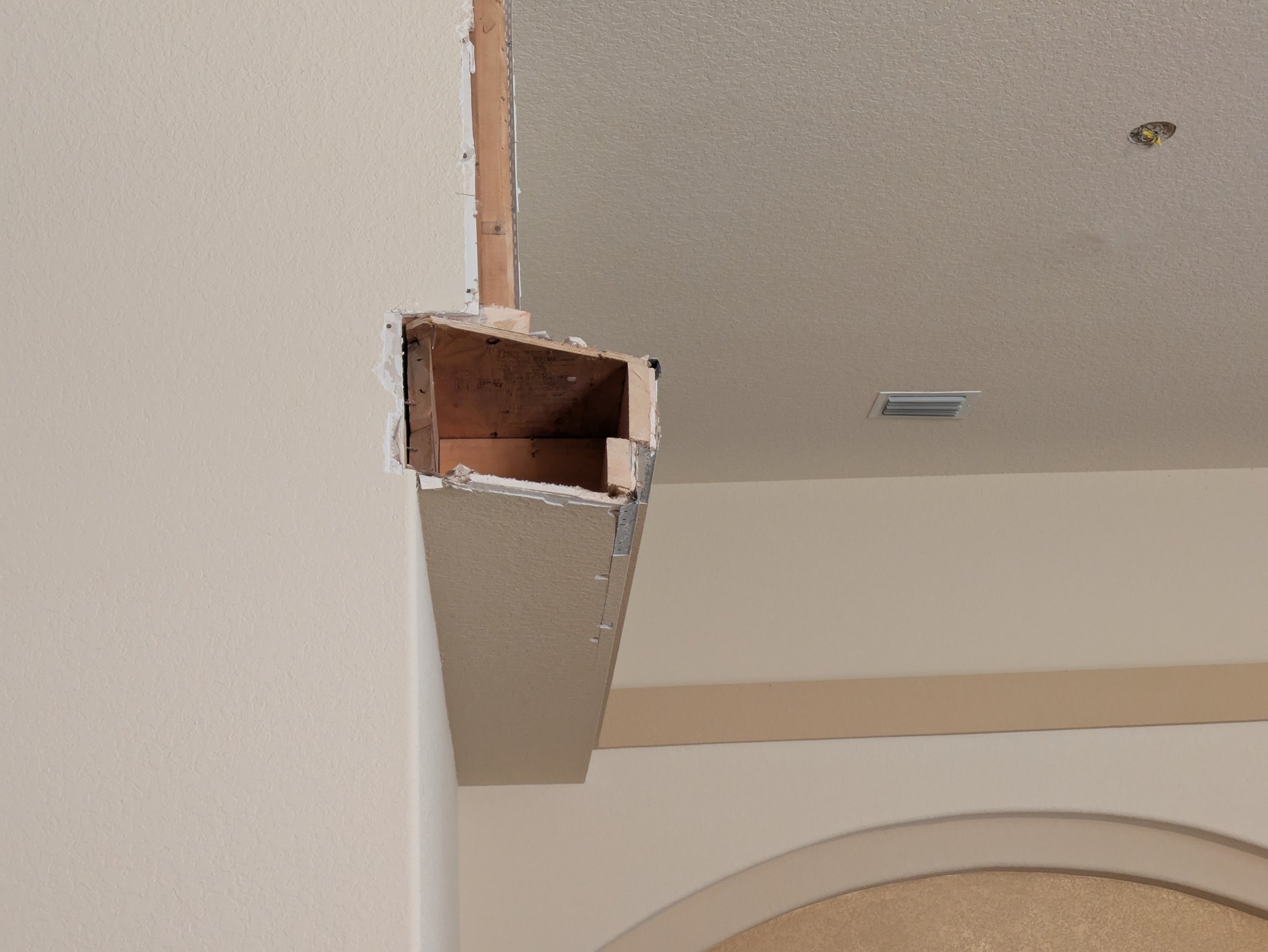 Open wall cavity with exposed wooden framing and drywall, indicating ongoing home renovation or remodeling.