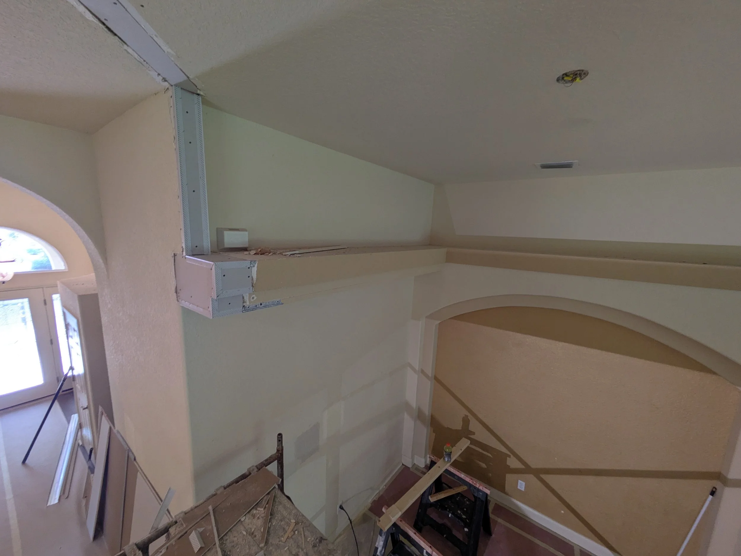 Interior room under construction with drywall installation, scaffolding, and construction tools.