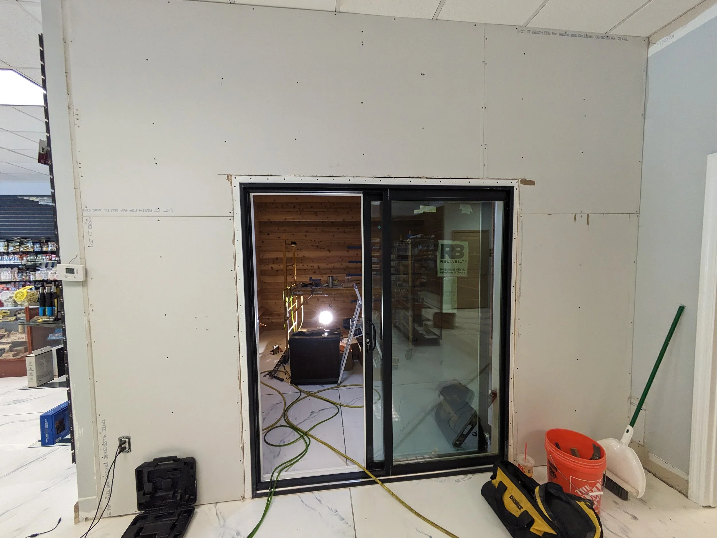 Construction site with a partially installed sliding glass door, tools, and equipment around.