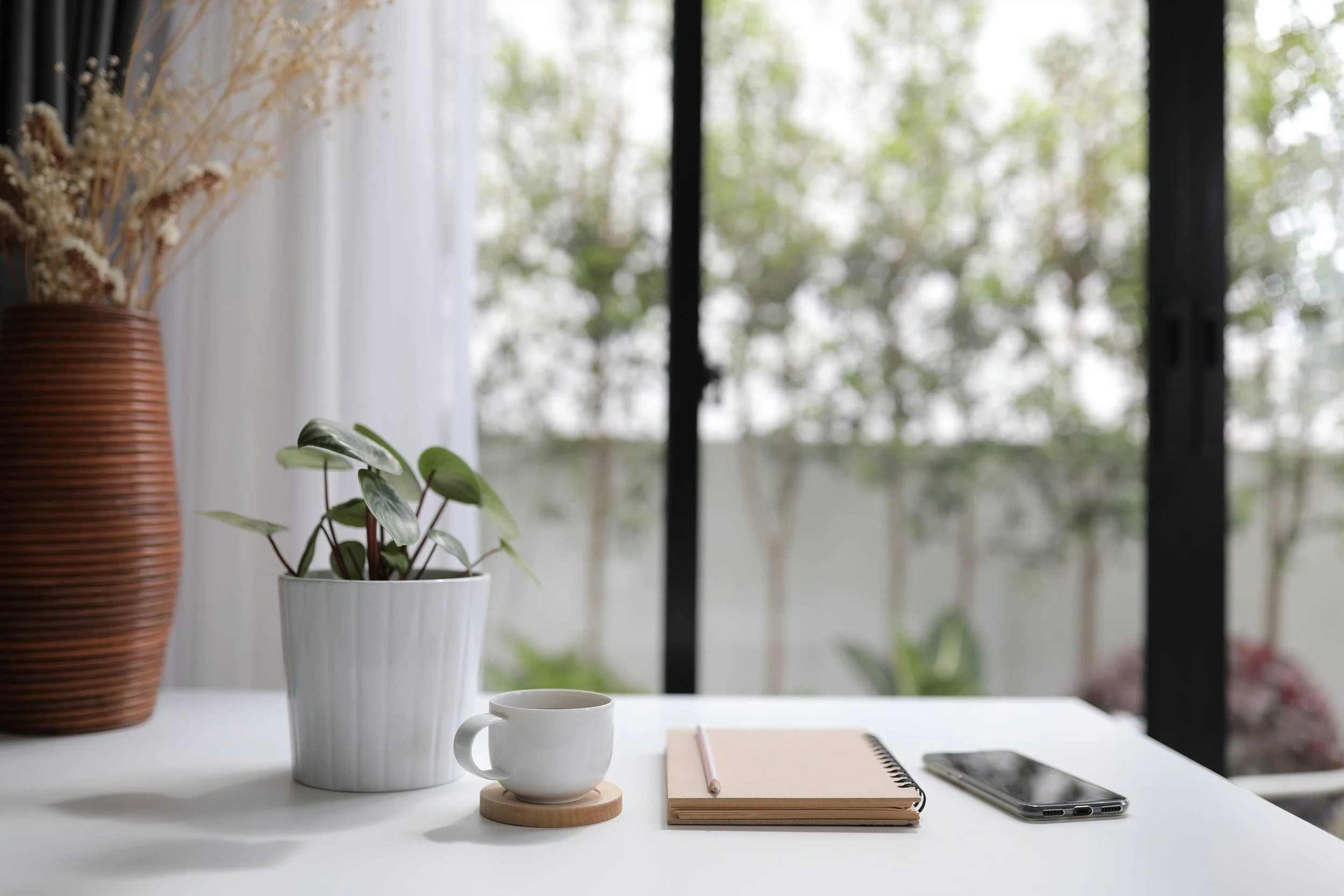Desk with potted plant, coffee cup, and notebook to represent supportive and active therapy at this New York City therapy practice located in Chelsea.