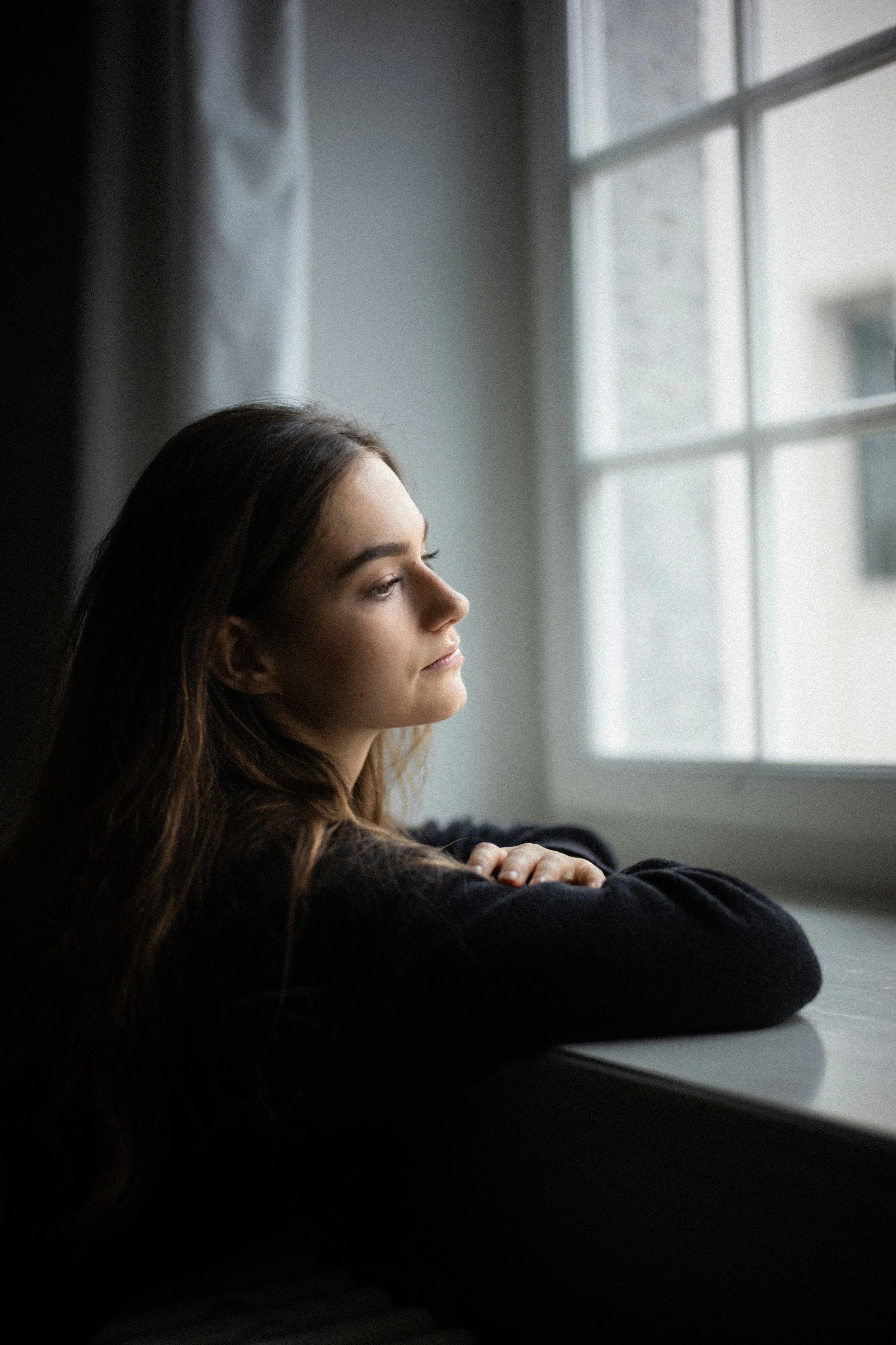 Woman looking out a window representing relationship anxiety and attachment insecurity.