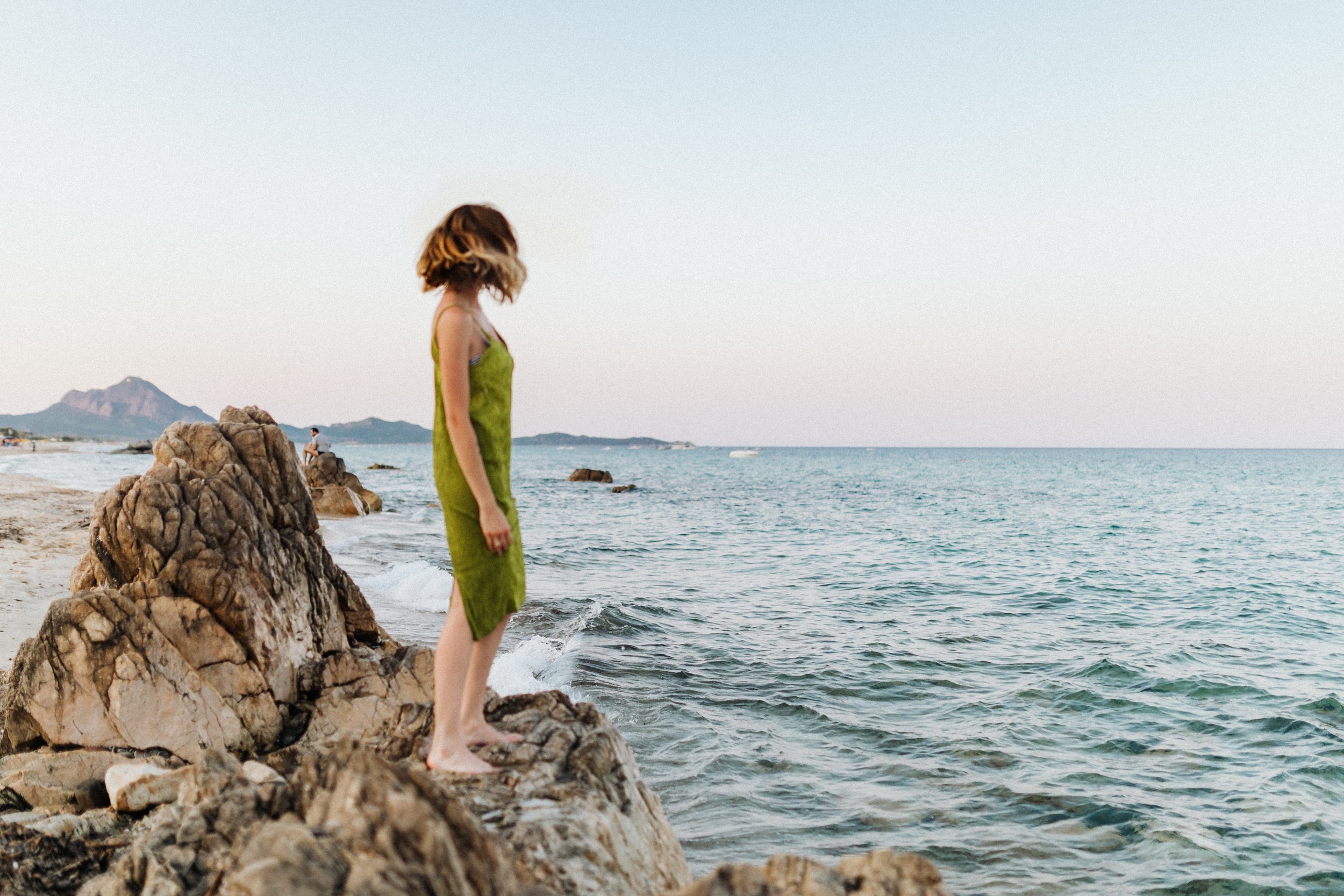 Woman looking at the sea standing on a rock, representing growth in therapy.