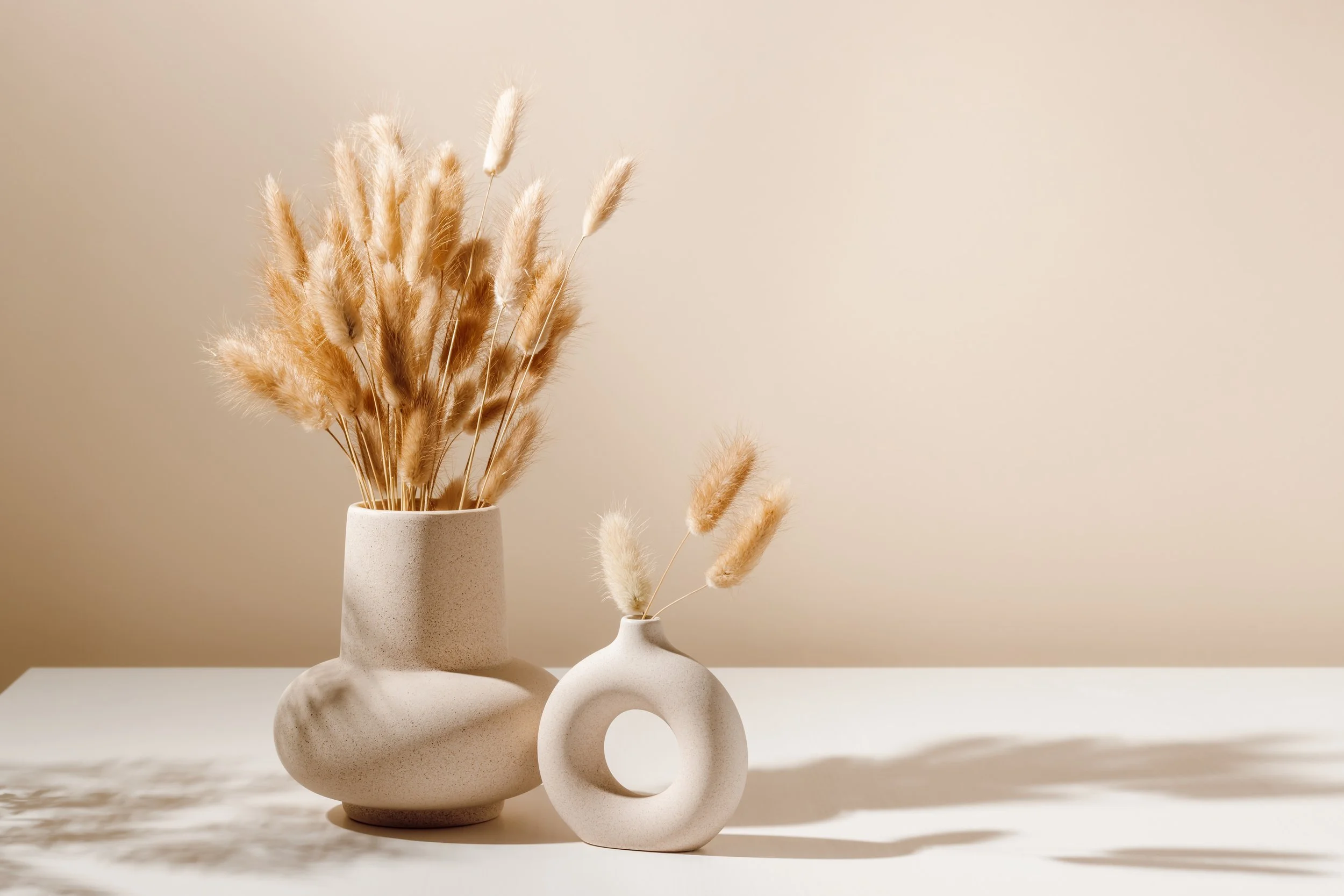 Two minimalist beige vases with dried pampas grass symbolizing connection and growth from a caring and warm therapist.